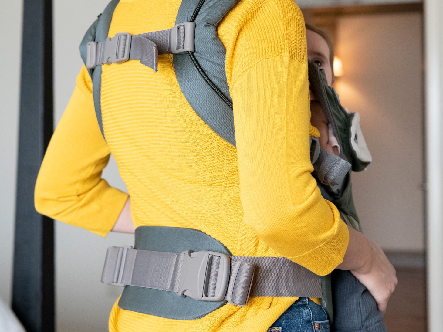 Back view of savvy 4-in-1 carrier buckles and pads on mom carrying baby