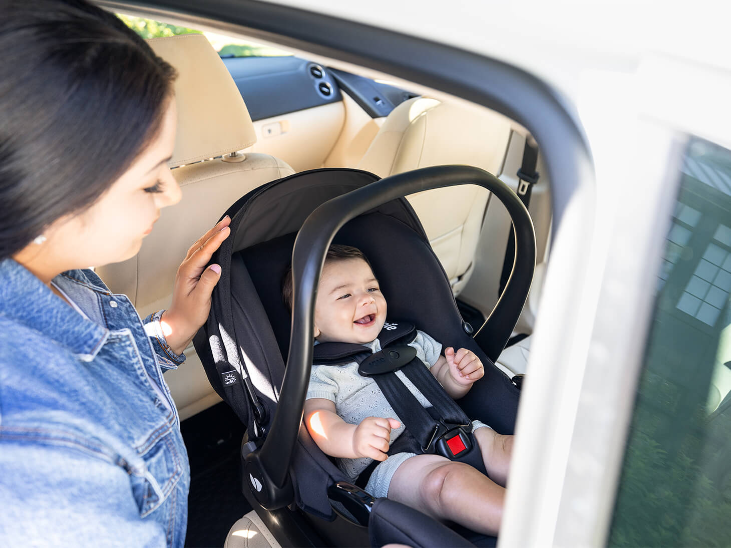 Happy baby buckled in car seat with mom.
