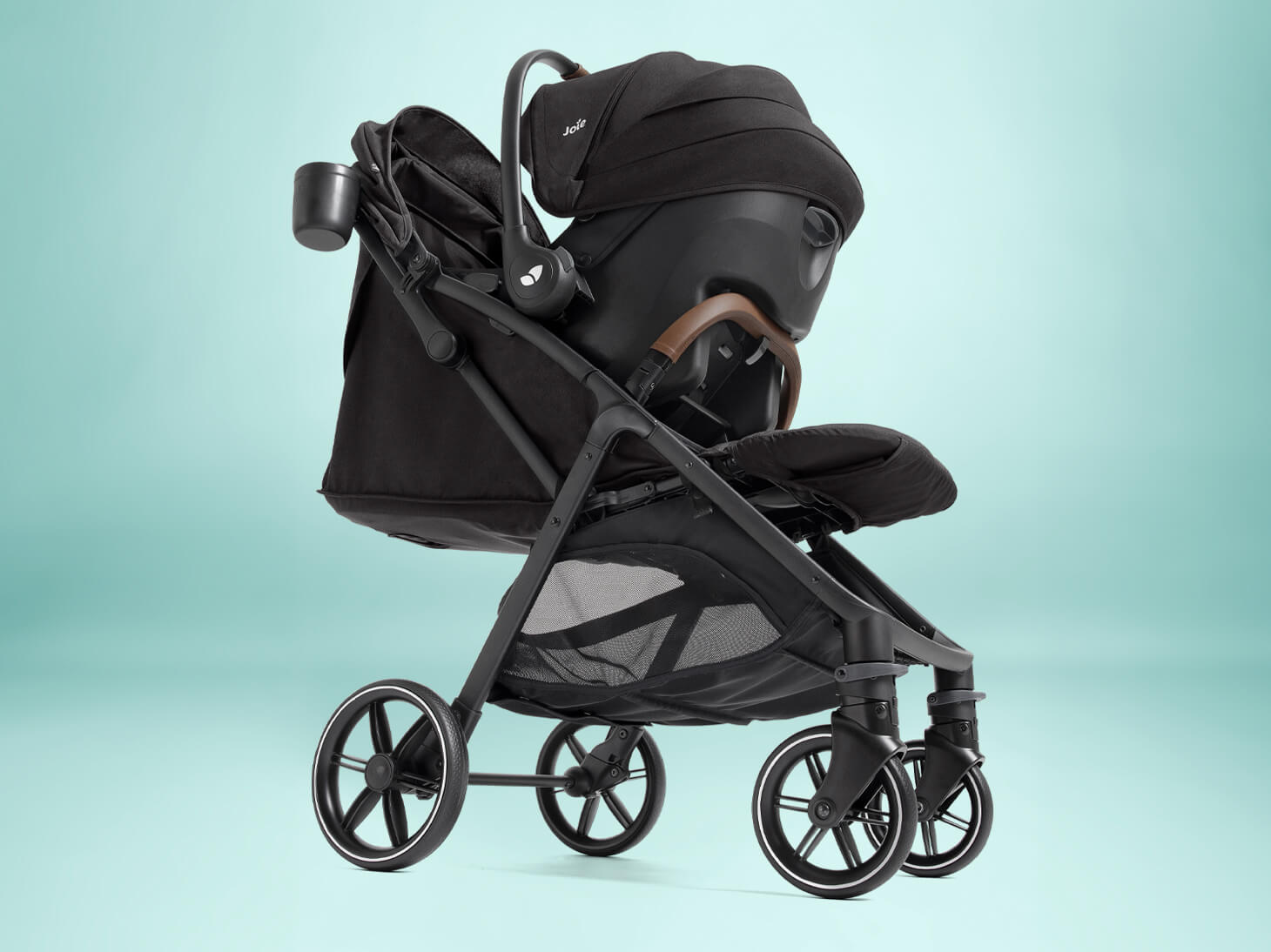 Mom pushing nutmeg compact stroller with mint latch infant car seat as travel system in city.
