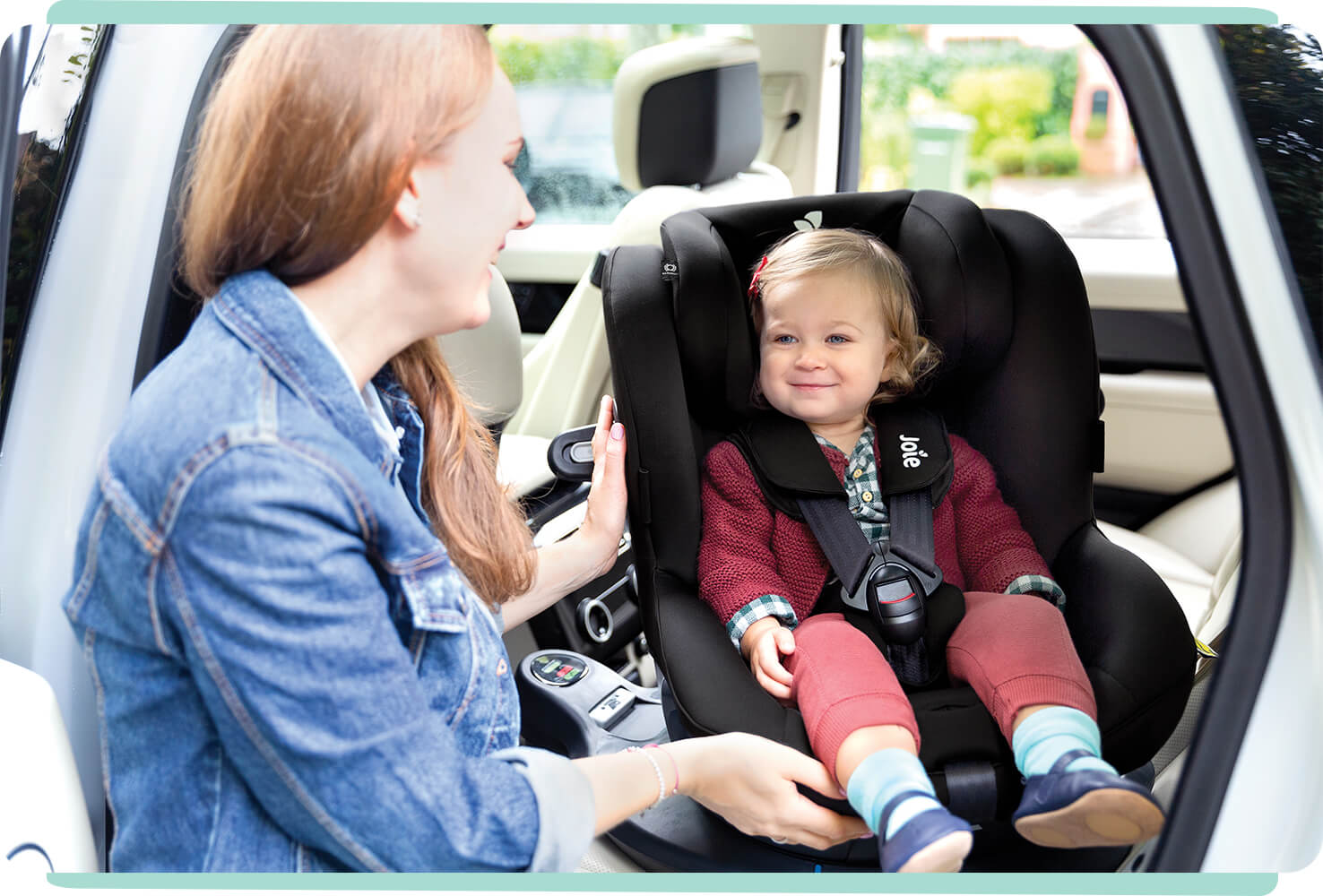 Mamá girando a su hija pequeña en posición contraria a la marcha en una silla de coche Joie I-Spin 360 en negro.