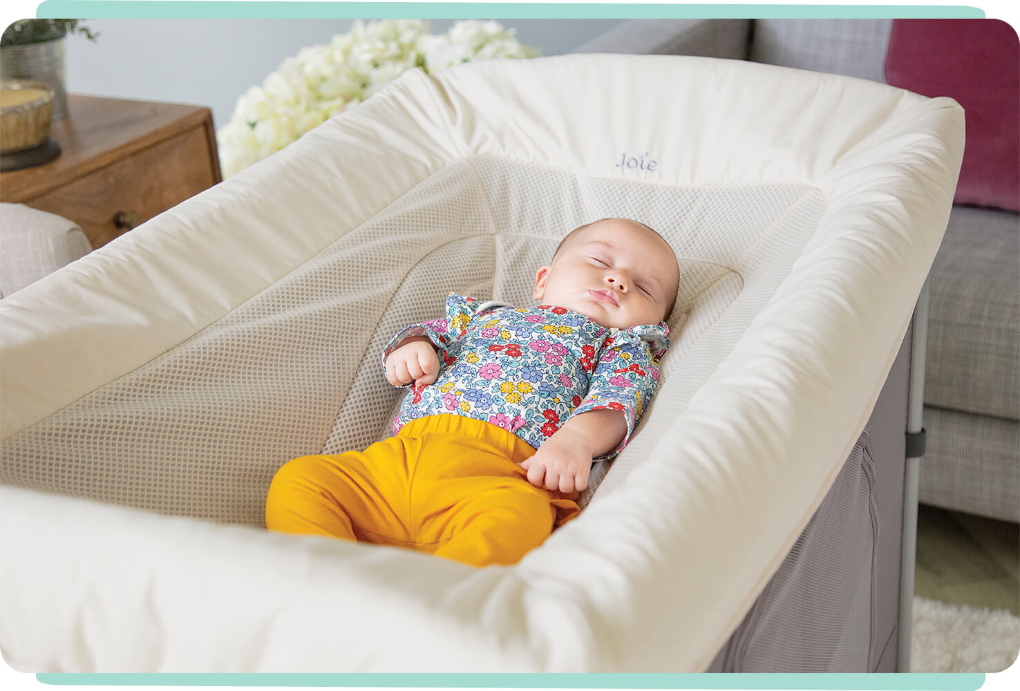 A baby sleeping in a cream colored Joie Daydreamer napping seat