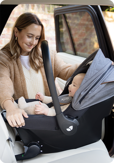 Bébé dans Sprint installé sur le siège arrière de la voiture par une mère joyeuse.