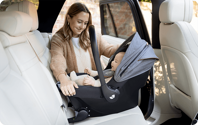 Baby in Sprint infant carrier being installed into back seat of car by happy mother